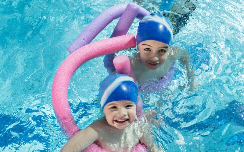happy children kids group at swimming pool class learning to swim.