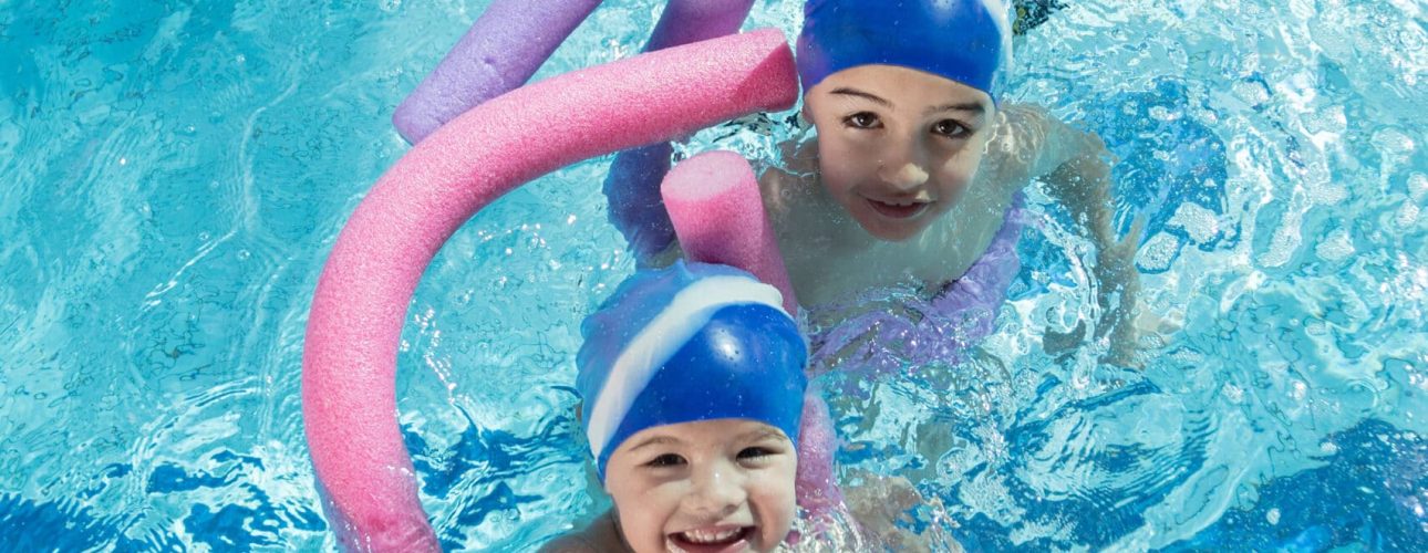 happy children kids group at swimming pool class learning to swim.